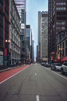 A bustling urban street flanked by tall skyscrapers and modern building facades under a clear sky.