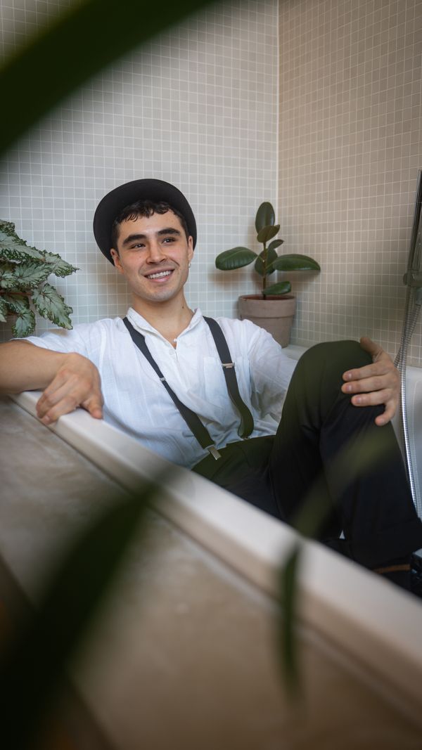 A man in a hat and suspenders sitting cheerfully in a bathtub — photo by Lillyfee_photography Linda Ohde on Pexels