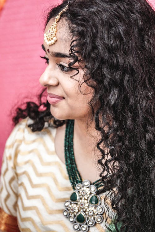 A woman with long curly hair and a necklace