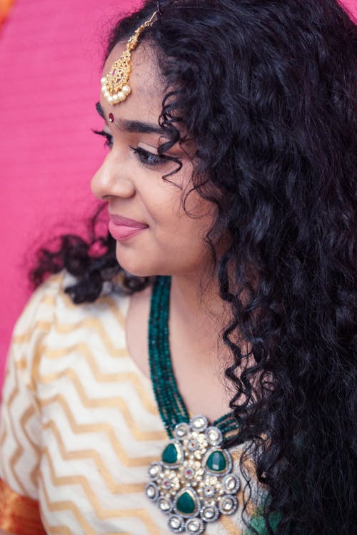 A woman with long curly hair wearing a gold necklace