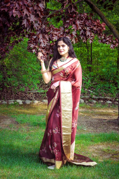 A woman in a maroon sari standing in the grass