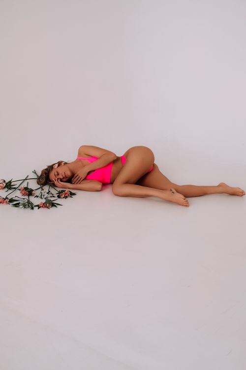 Free A woman in pink lying gracefully on the floor with delicate flowers around her. Stock Photo