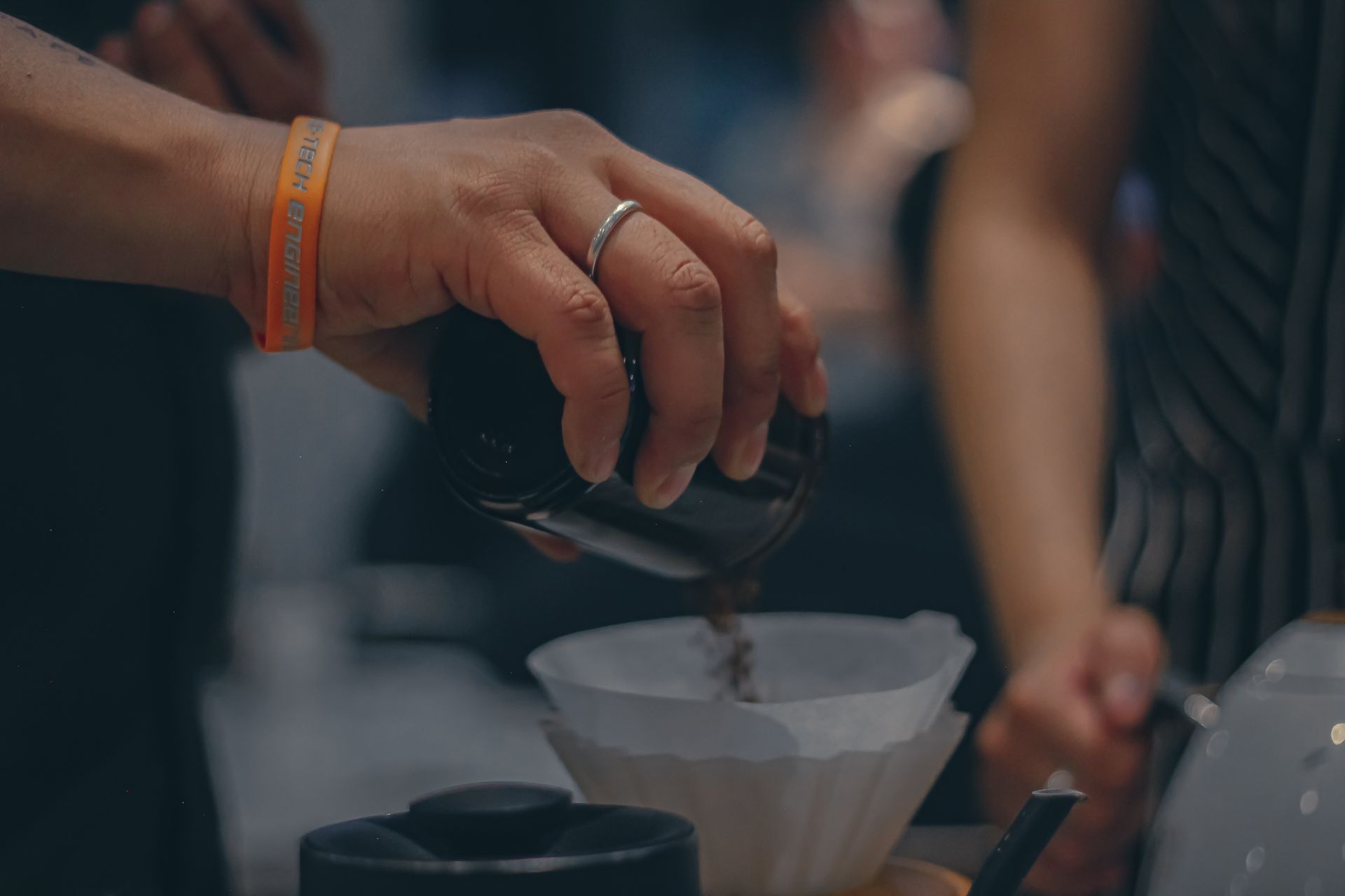 A detailed view of fresh coffee grounds being poured into a filter by hand, showcasing the brewing process.
