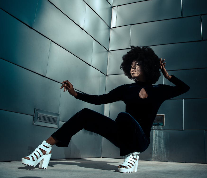 Young Woman in Fashionable Clothes Posing against a Wall of a Modern Building 