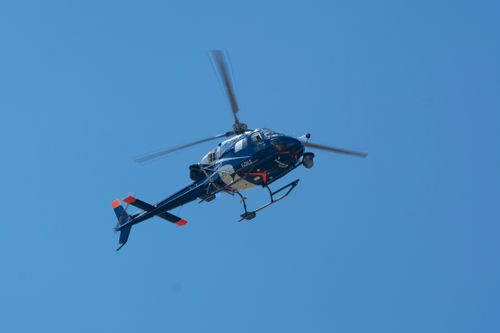 Free A blue helicopter is prominently flying against a clear sky, showcasing its aerodynamic design and motion. Stock Photo