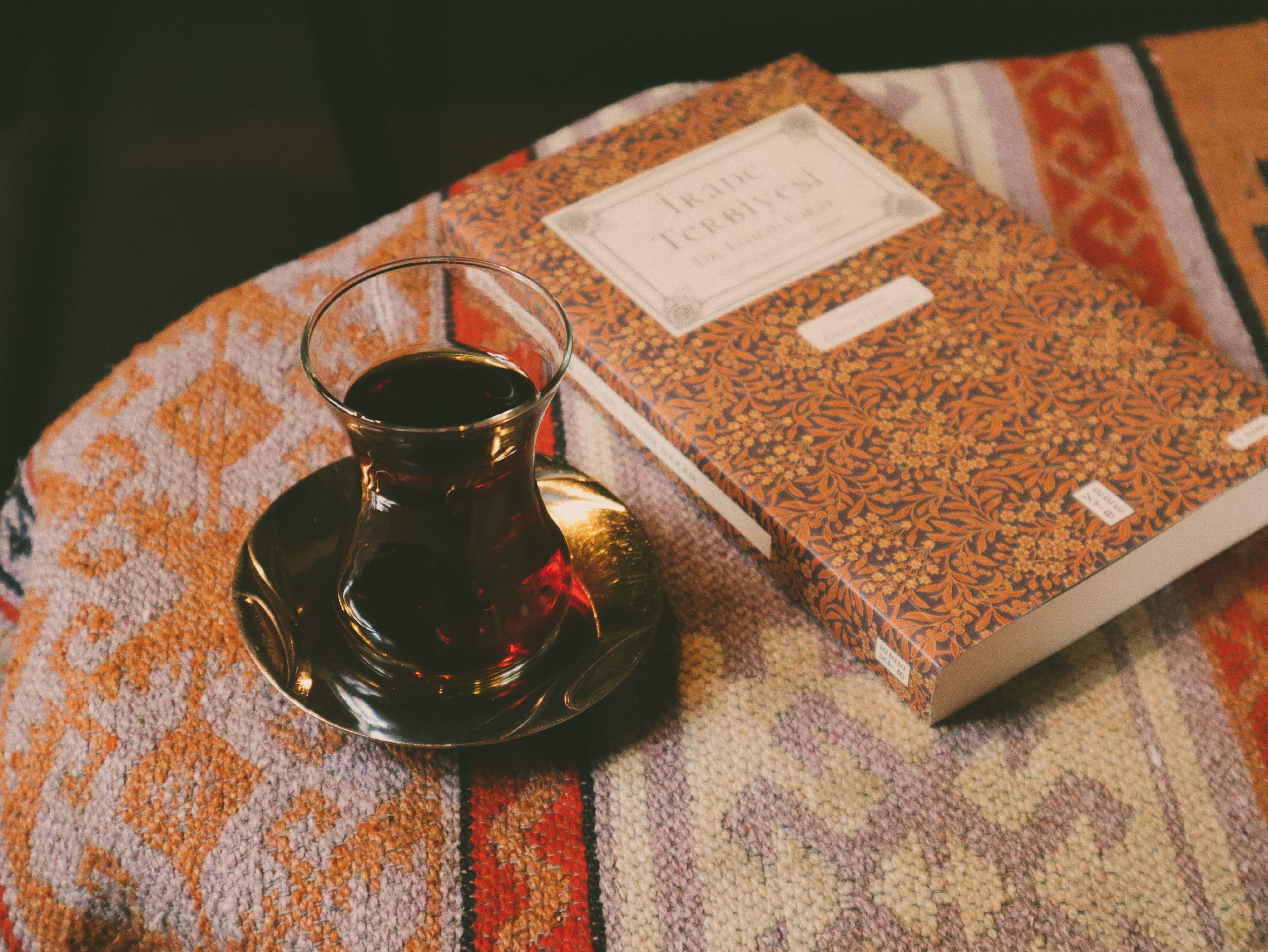 A warm scene with Turkish tea and a book on a vintage patterned rug, creating a cozy atmosphere.