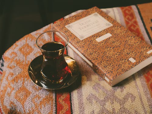 A cup of tea sits on a table next to a book