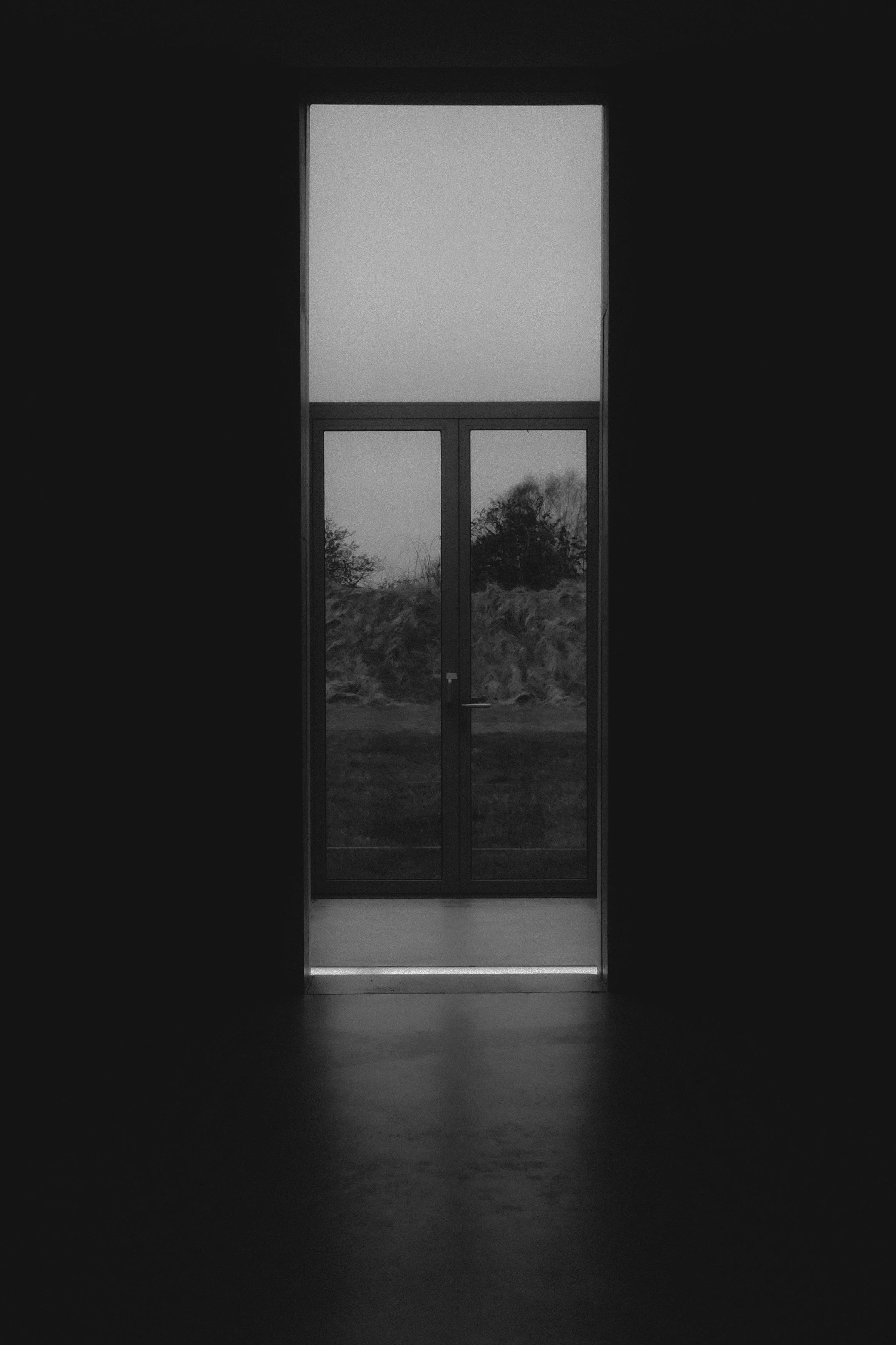 Dark interior with a large vertical window providing contrast and light.