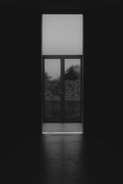 A black and white photo of a door with a window