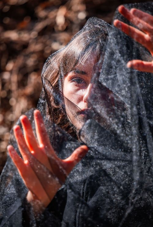 Free Captivating portrait of a woman with a veil casting intricate shadows outdoors. Stock Photo