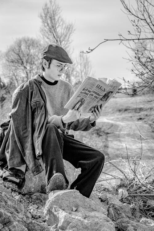 Man Sitting with Newspaper in Countryside in Black and White