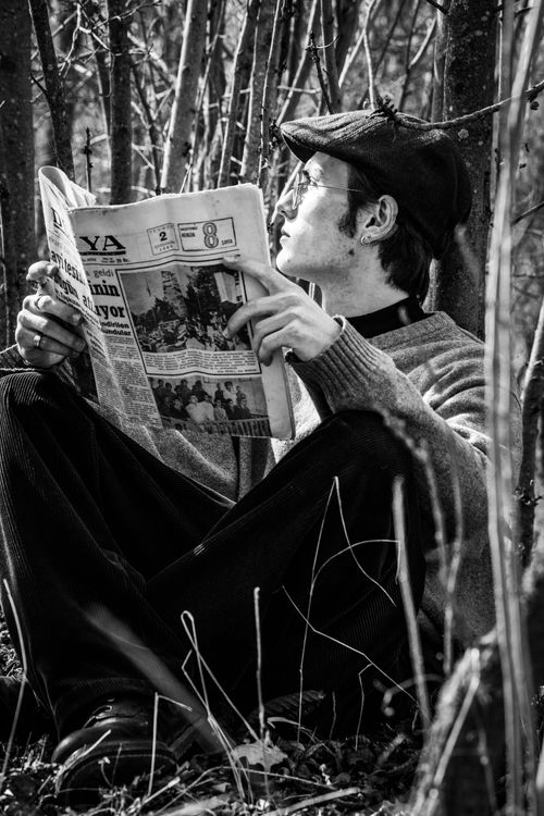 Free A man sitting outdoors reading a newspaper in a black and white setting. Stock Photo