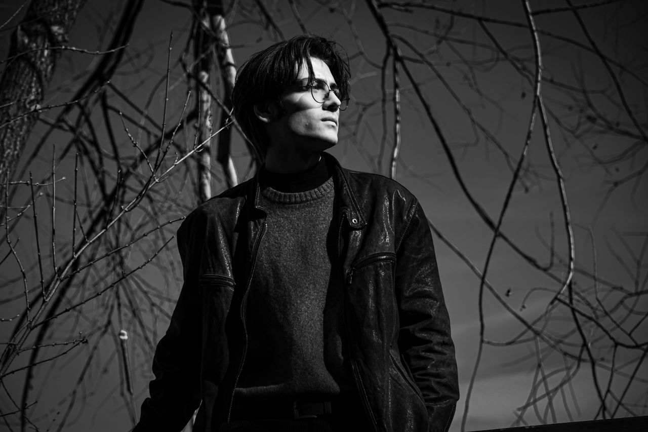 stylish black and white portrait of a man in a leather jacket standing
