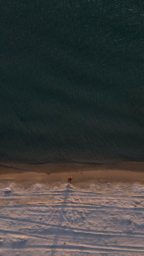 Person Standing on Beach in Snow