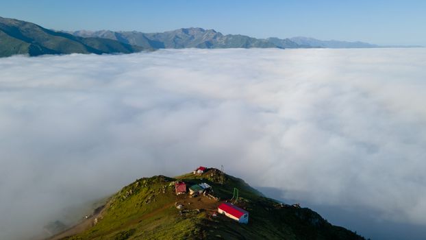 Drone view of Yukarışimşirli village atop mountains and clouds, in Rize, Türkiye.