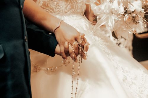Free Close-up of a bride and groom holding hands with a rosary at their wedding in Tlaxcala, Mexico. Stock Photo