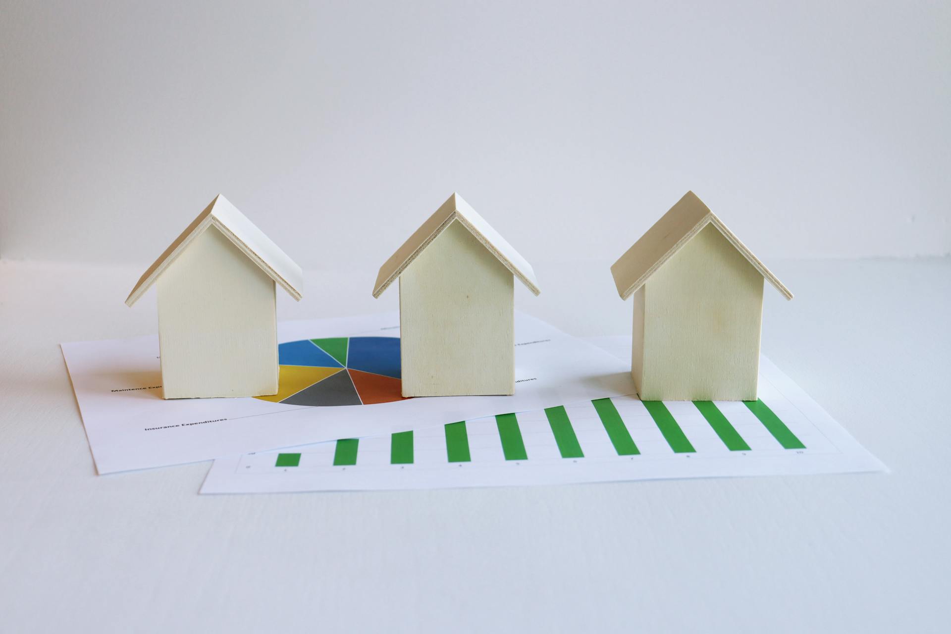 Wooden model houses on graphs depict real estate market analysis and trends.