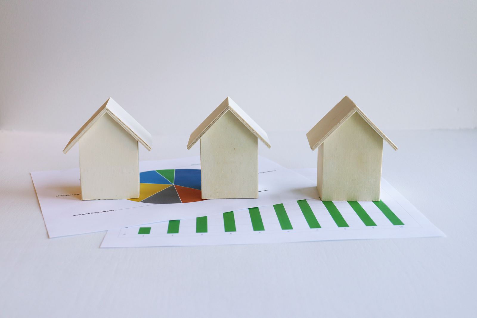 Wooden model houses arranged next to printed graphs representing the housing market