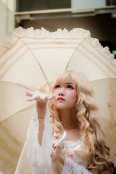 一位身着角色扮演服装的美丽亚洲女子，在阳光明媚的户外撑着伞摆姿势