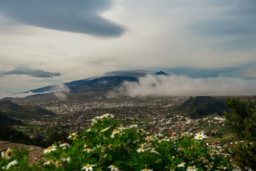 A view of a city and mountains with clouds in the sky