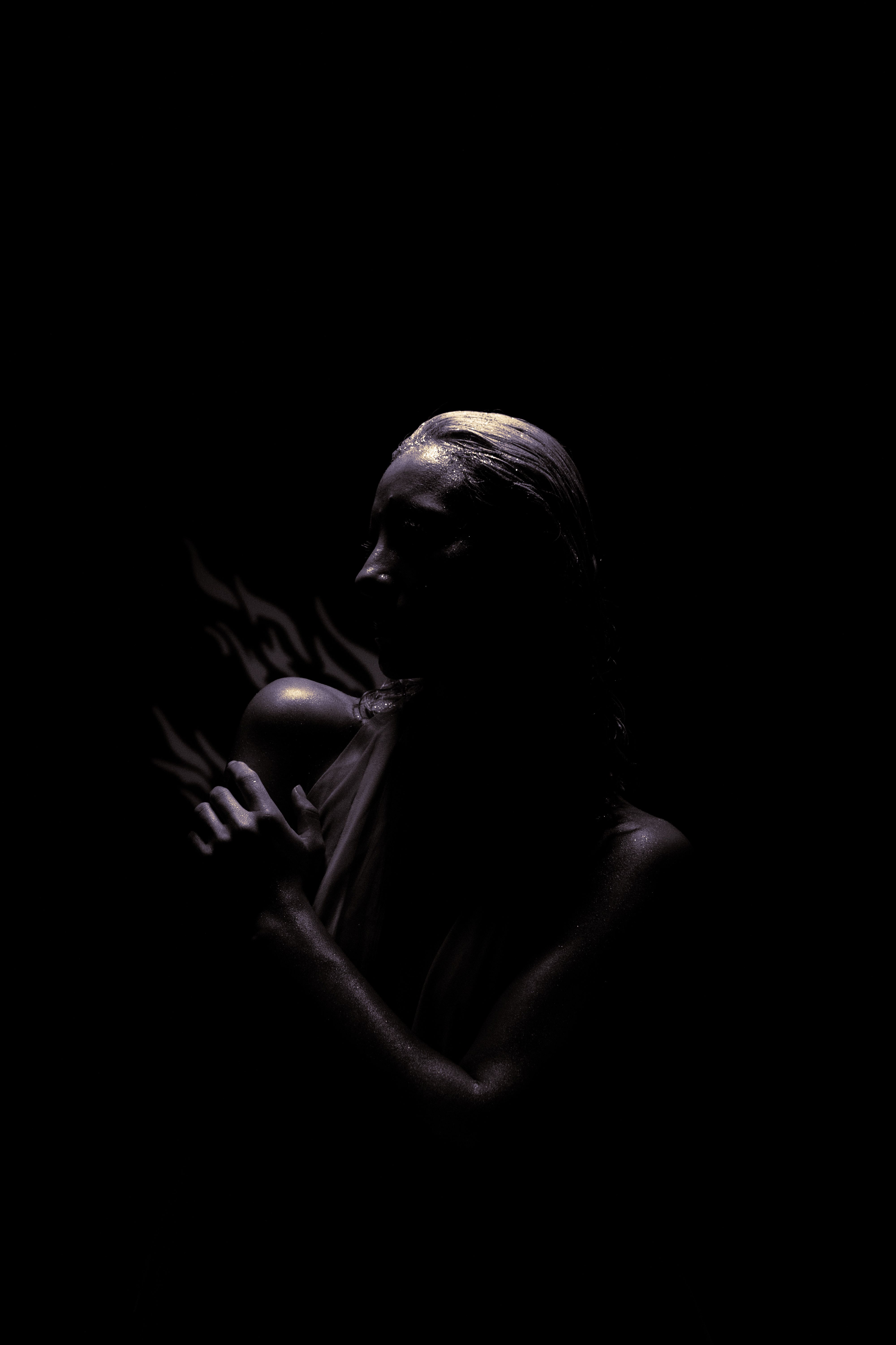 Artistic low-key portrait of a woman with dramatic lighting on a black background.. artistic, portrait, woman