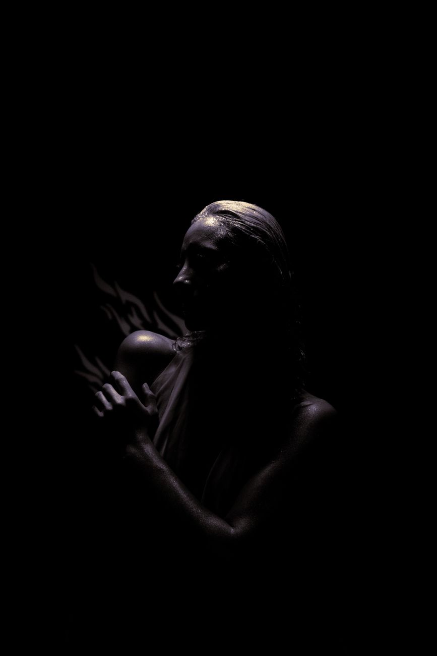 Artistic low-key portrait of a woman with dramatic lighting on a black background.. artistic, portrait, woman