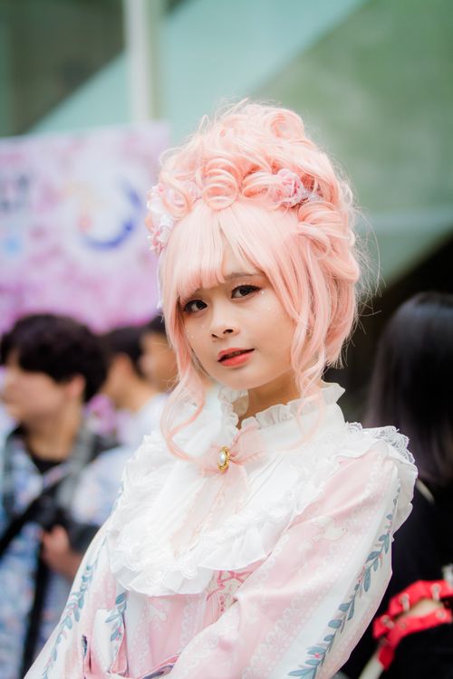 Free Beautiful woman in Victorian-themed cosplay with pink hair poses elegantly outdoors. Stock Photo