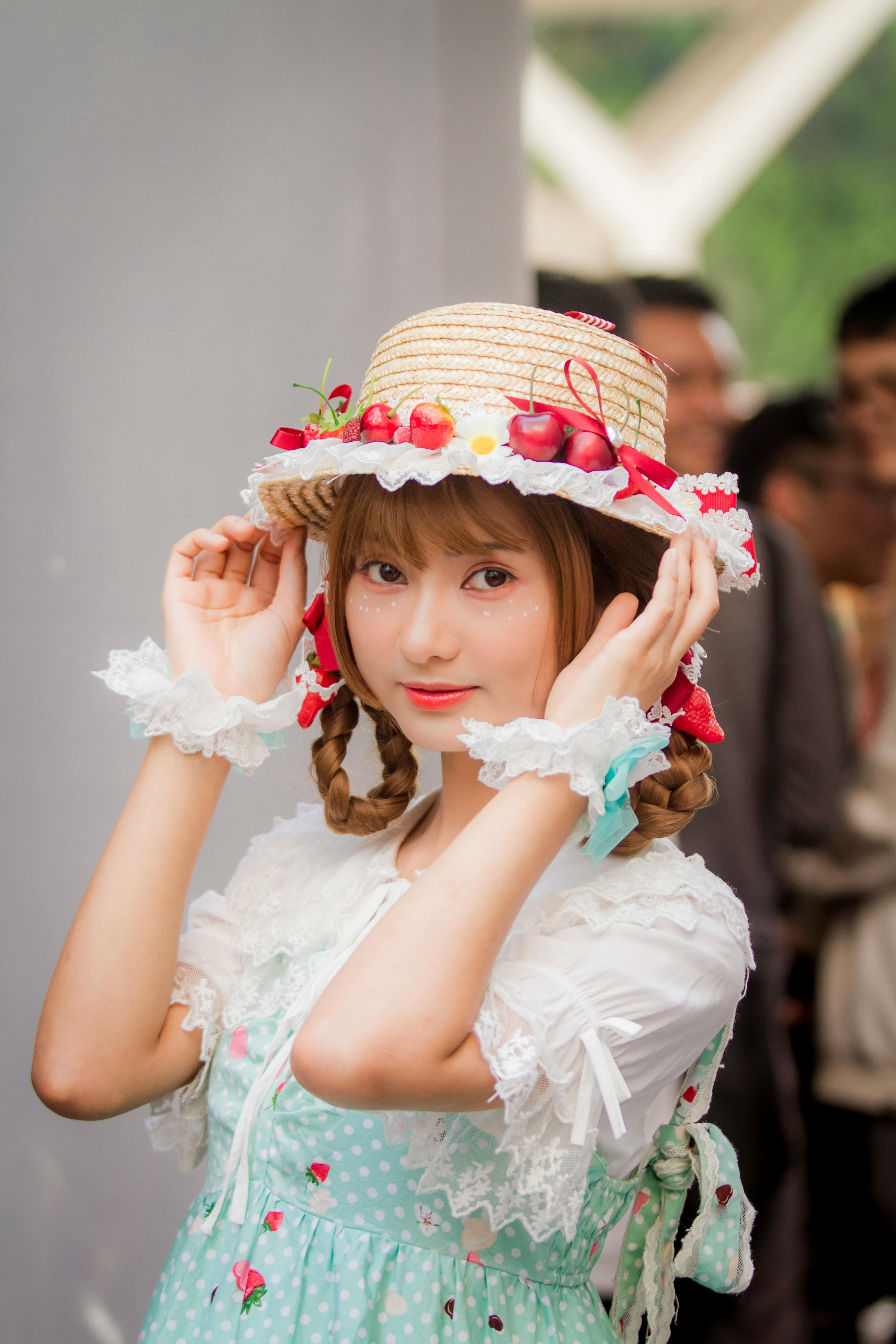 一位年轻女子身着带图案的连衣裙，头戴装饰着饰品的草帽