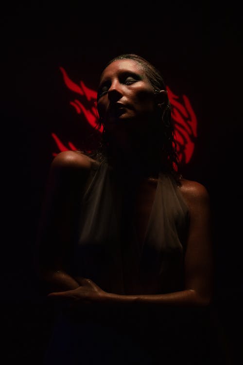 A woman in a white dress with red light behind her
