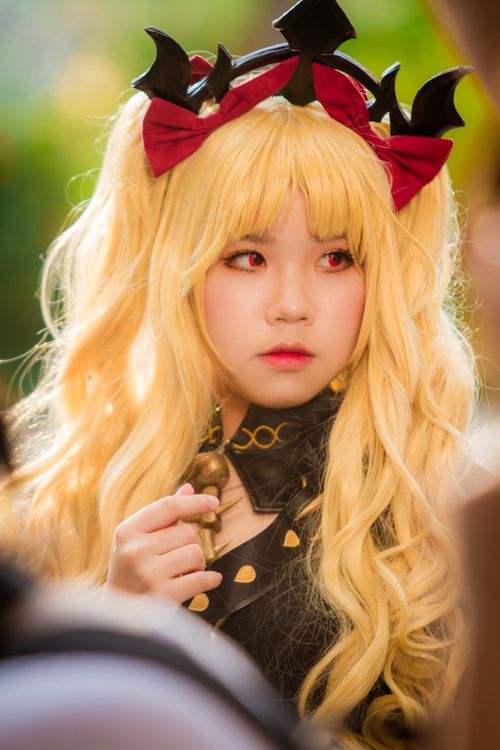 Free A blonde cosplayer wearing a fantasy costume with bows and long curly hair, posing outdoors. Stock Photo