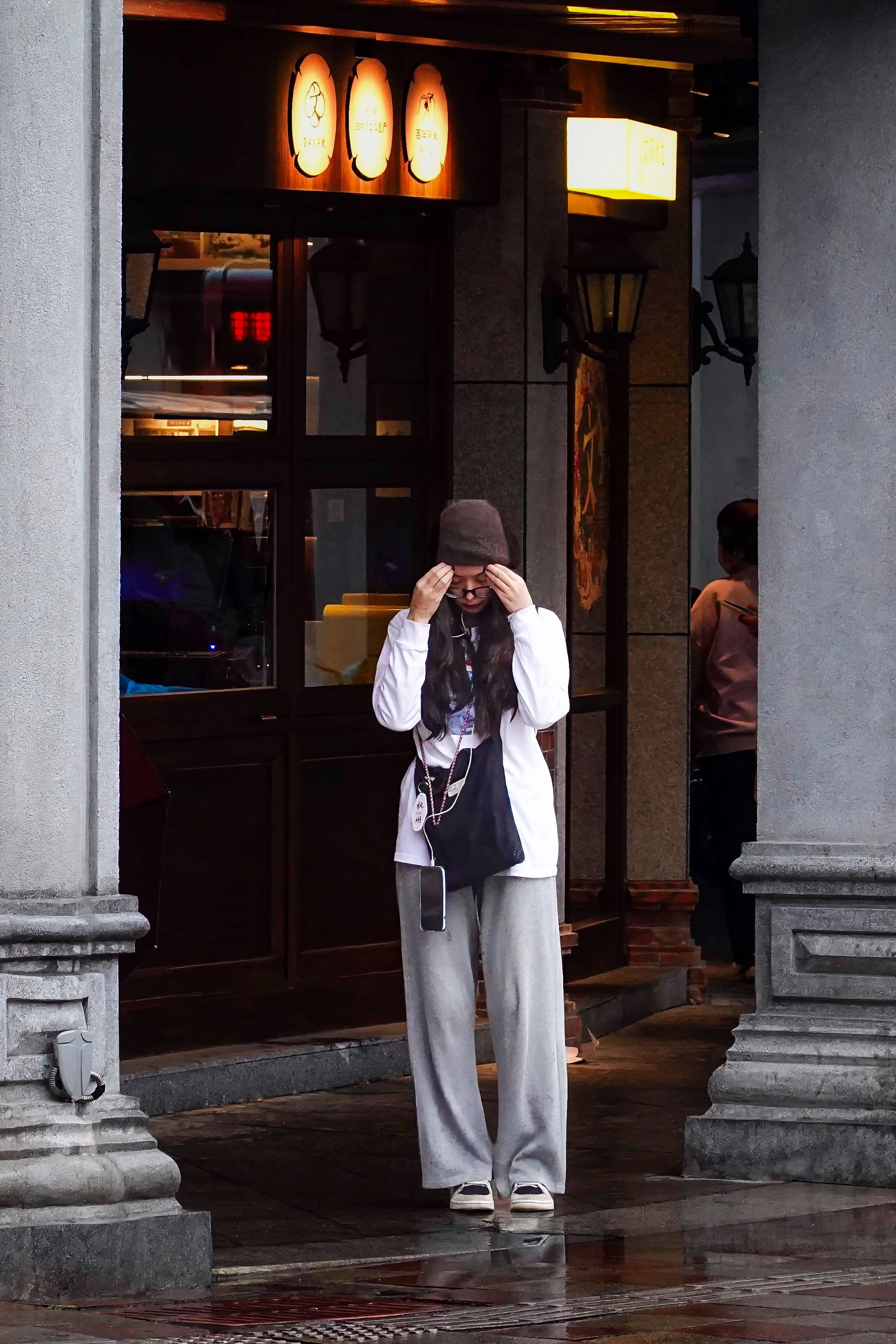 Woman in stylish attire stands beneath elegant arches in Quan Zhou Shi, China.