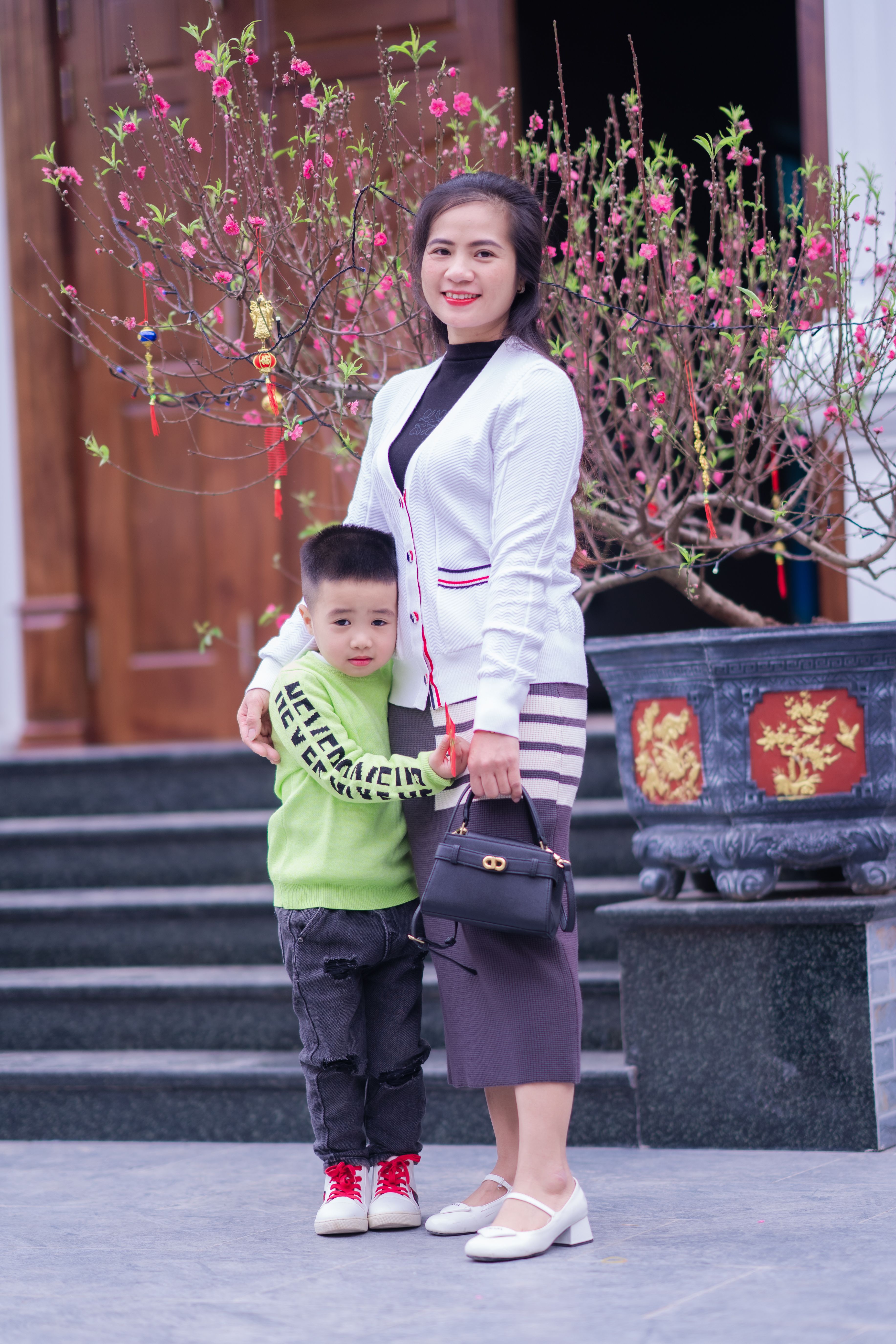 A mother and son standing together outdoors, smiling confidently