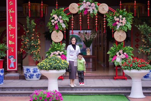 Free Mother and son posing at a vibrant floral entrance with festive decor. Stock Photo