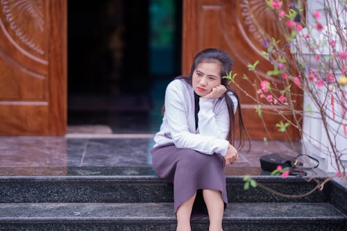 Young Woman Sitting on the Steps in Front of a Building 