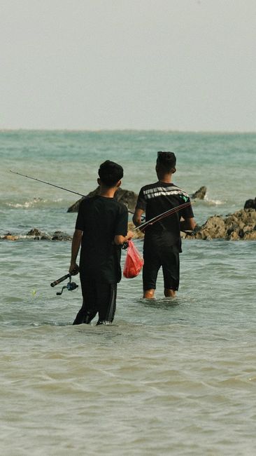 Pemancing sedang memilih spot strategis di tepi sungai untuk memancing ikan