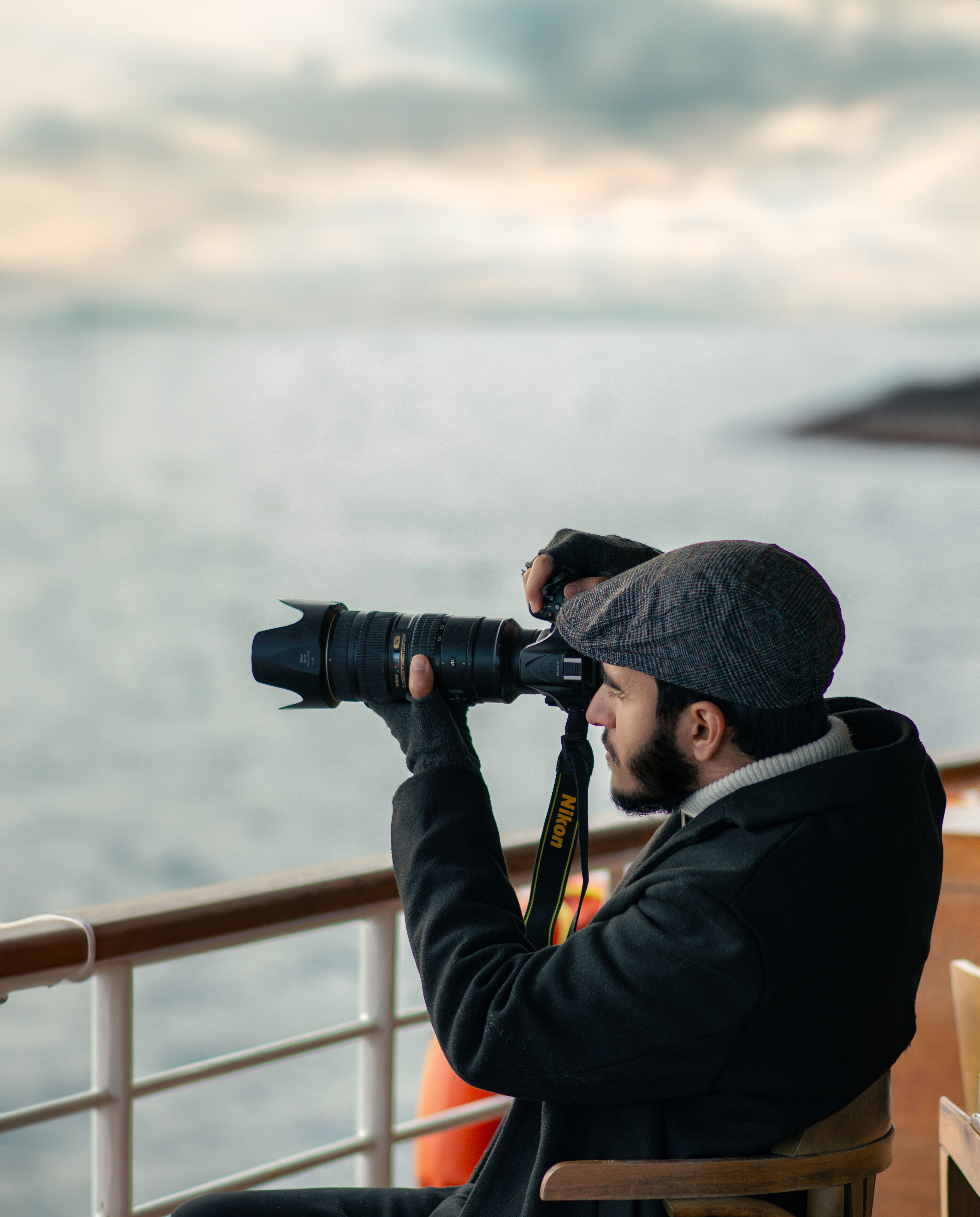 Man taking photos with a camera on ferry at dawn, capturing the scenic sea view.