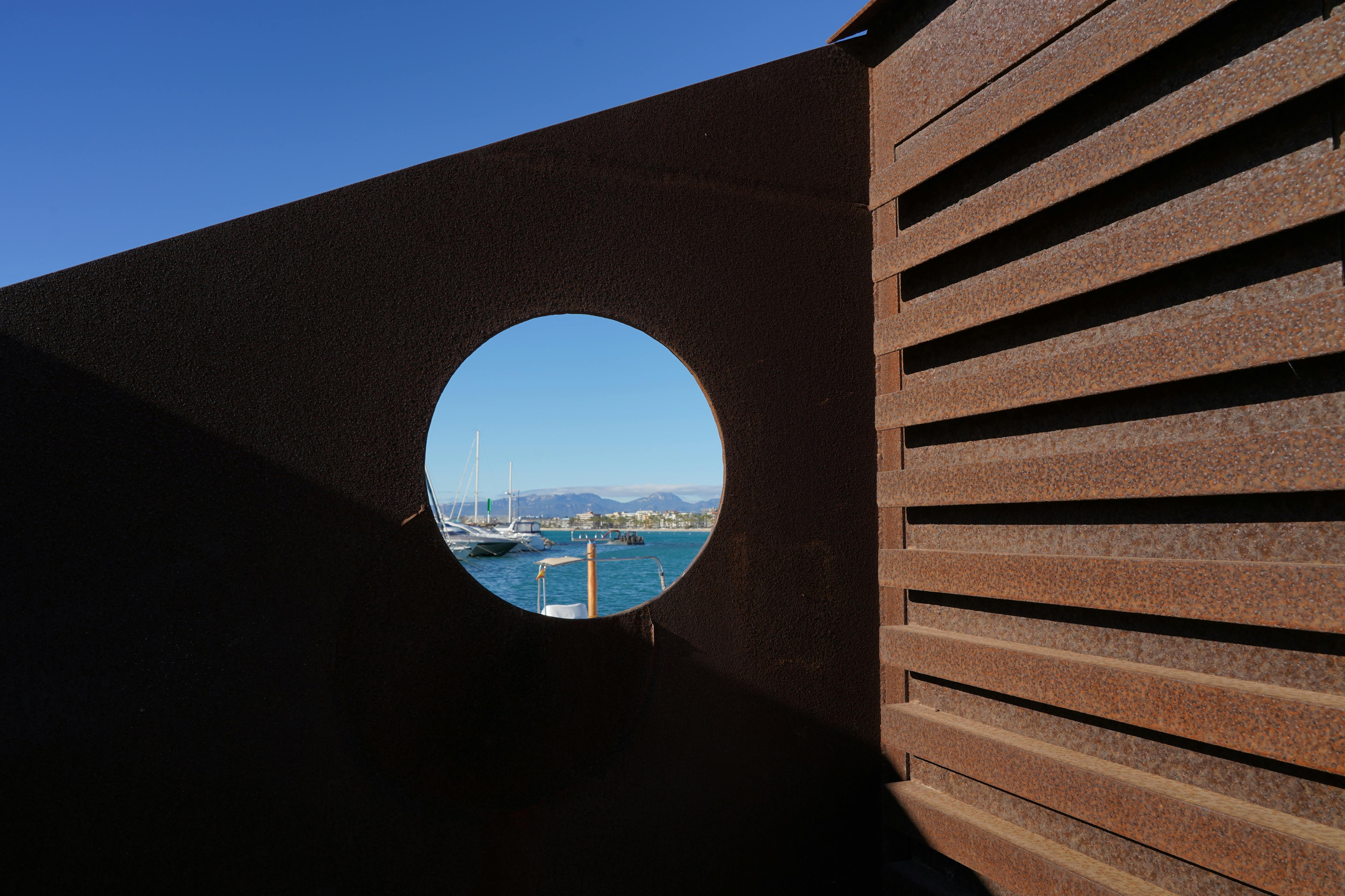 Unique perspective of Salou harbor seen through a round window frame.