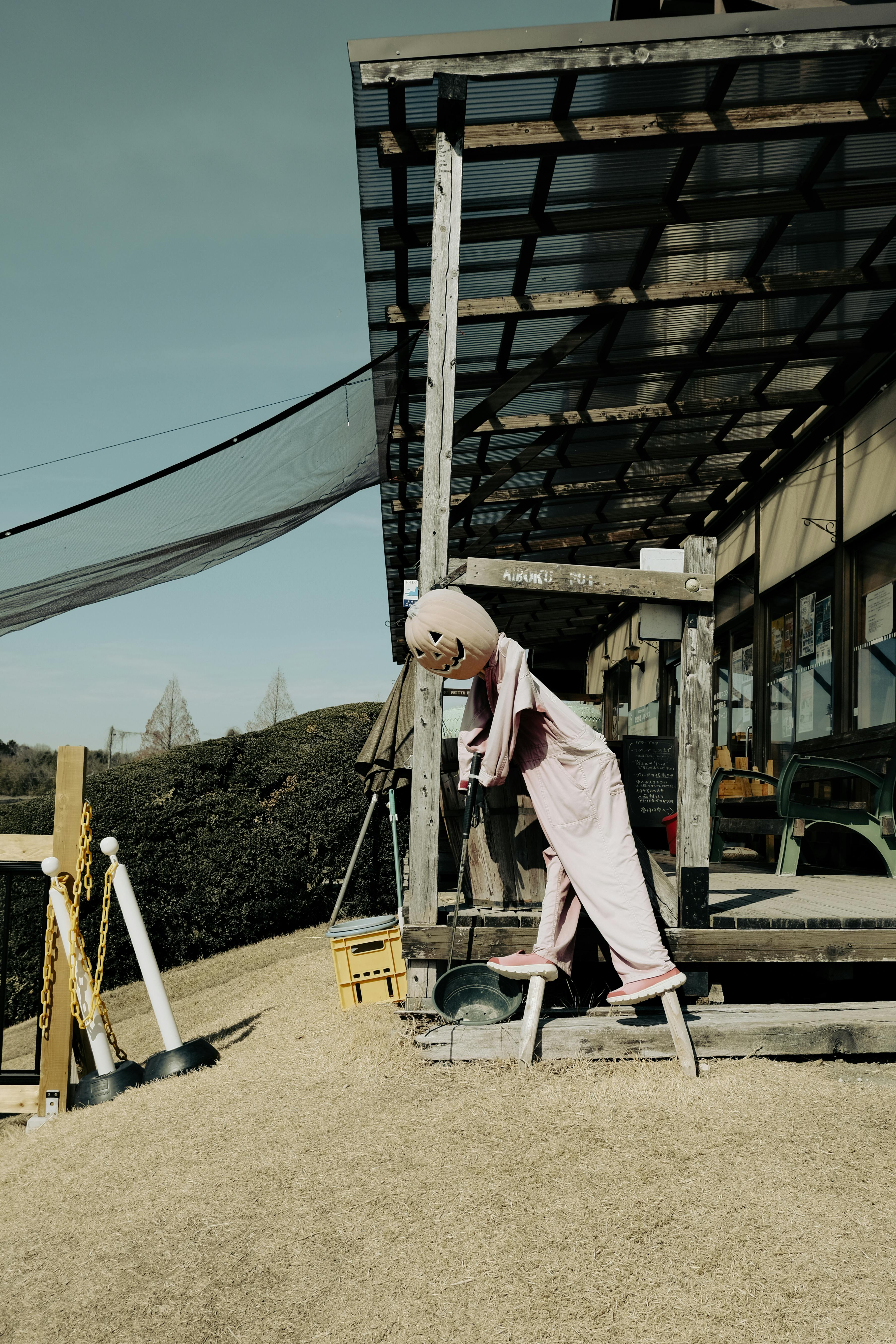 A quirky scarecrow stands on a rural porch captured in Toyota, Japan.