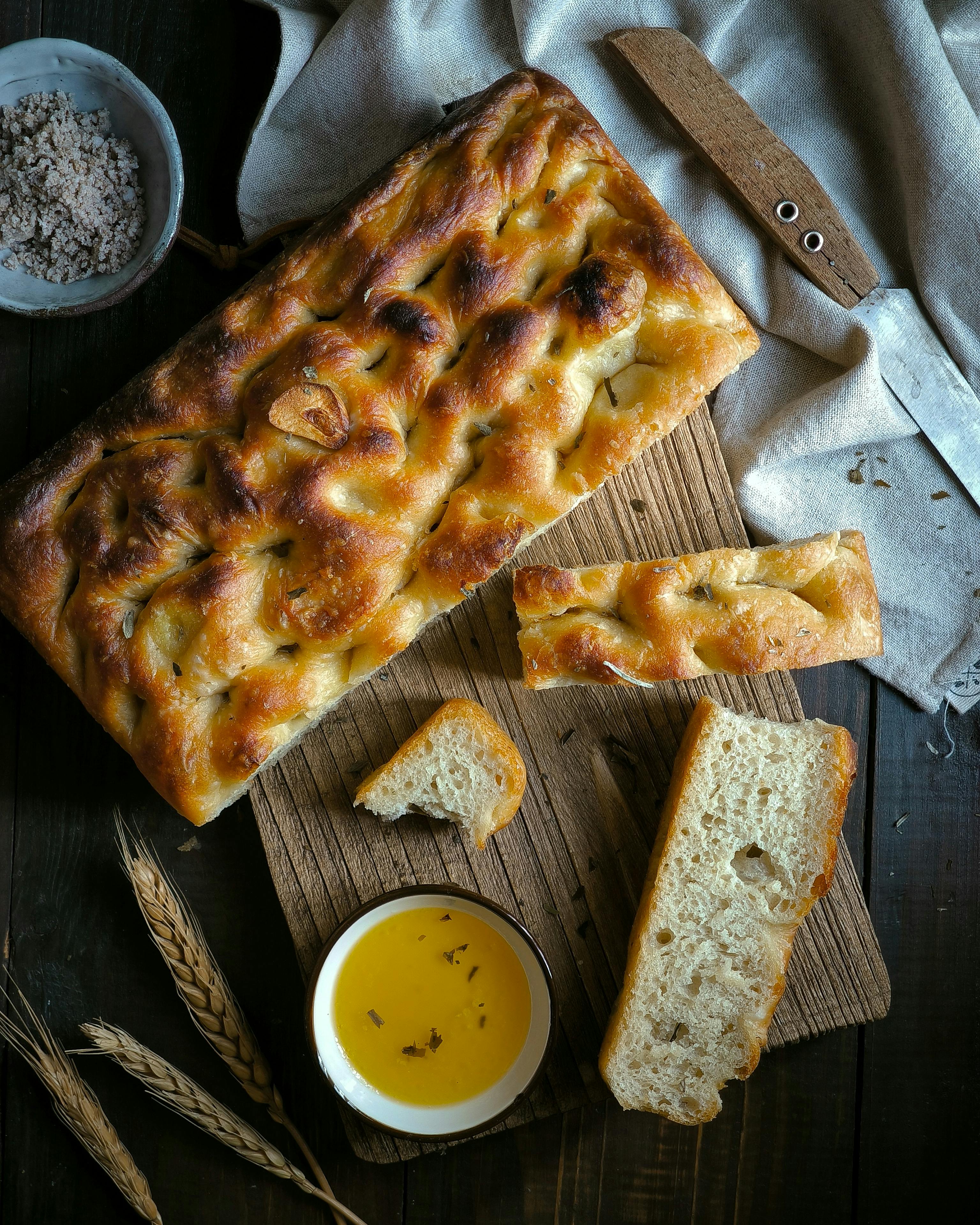 Freshly baked homemade focaccia bread served with olive oil, showcasing rustic charm.