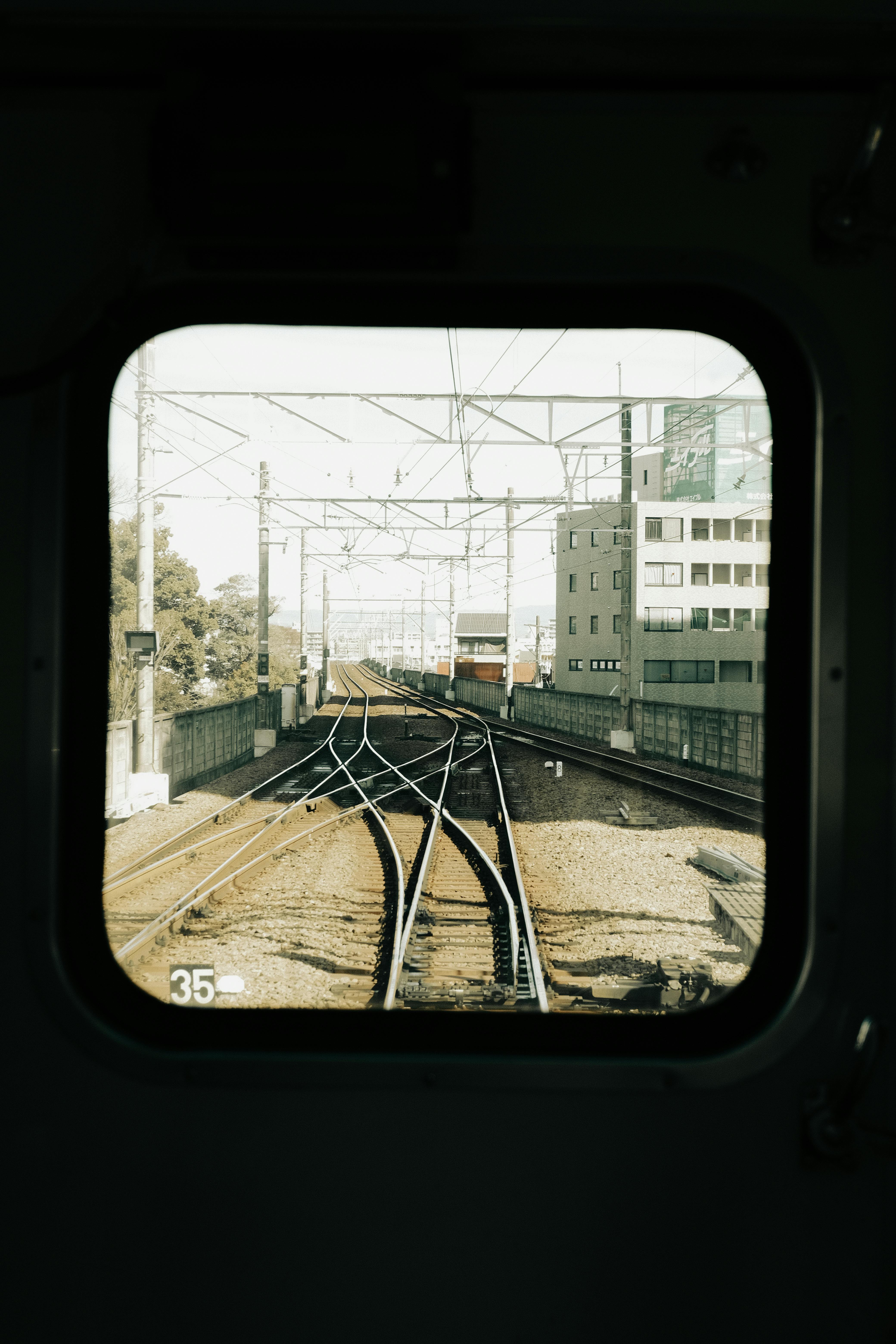 View of railway tracks from train window, capturing urban Japan's transit system.