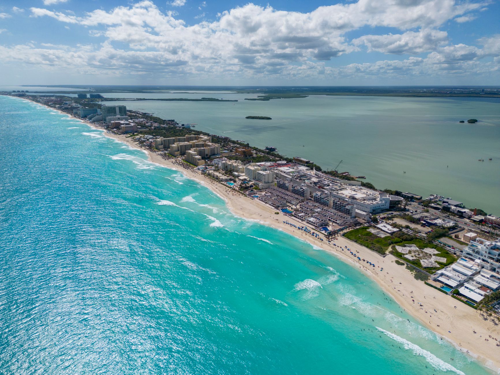 Aerial view of Cancun's pristine beaches and turquoise waters on a sunny day.