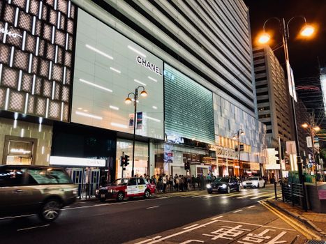 Vibrant nightlife scene capturing cars and people in Kowloon's shopping district, Hong Kong.