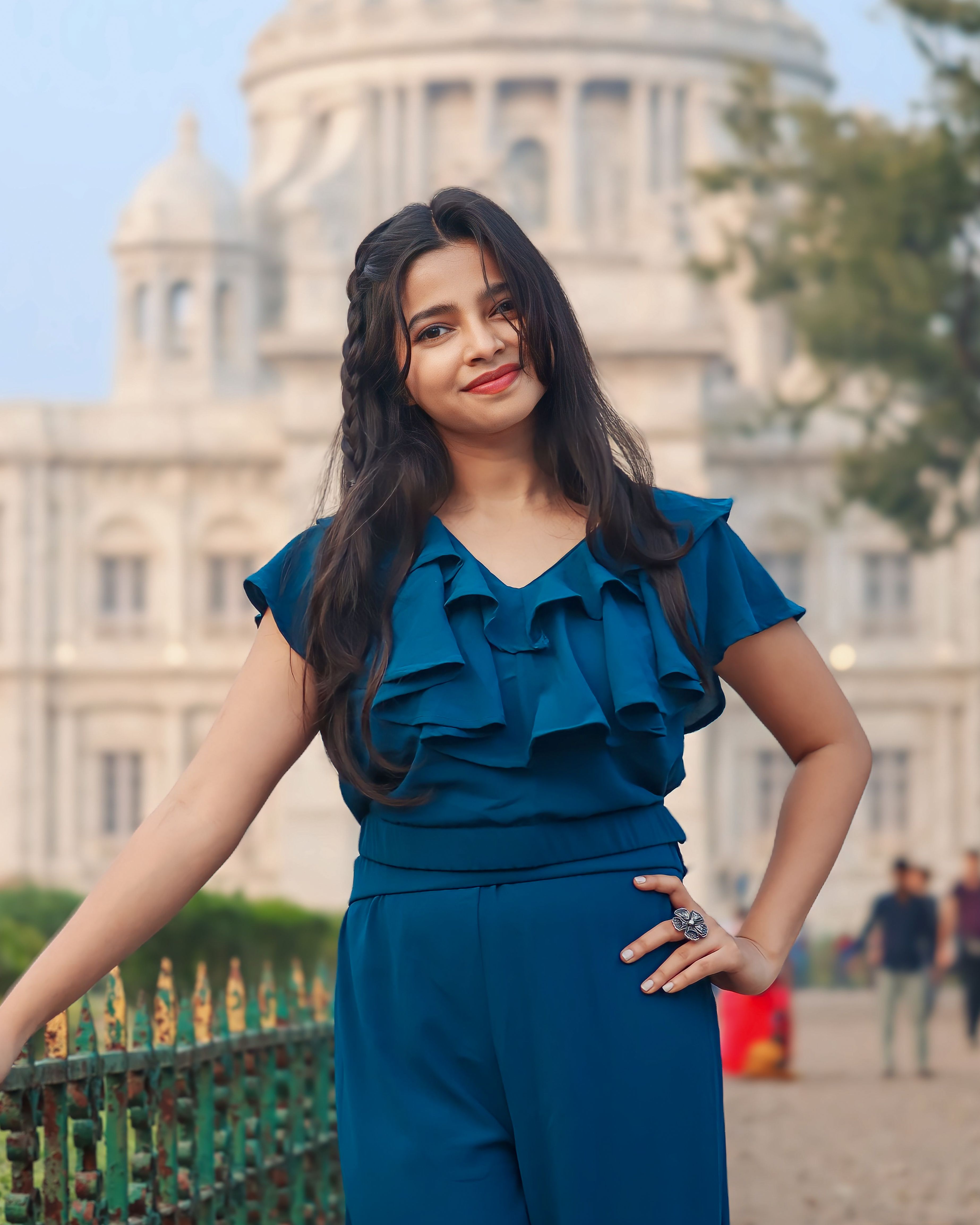 A young woman in a blue outfit poses confidently in front of Victoria Memorial, Kolkata.