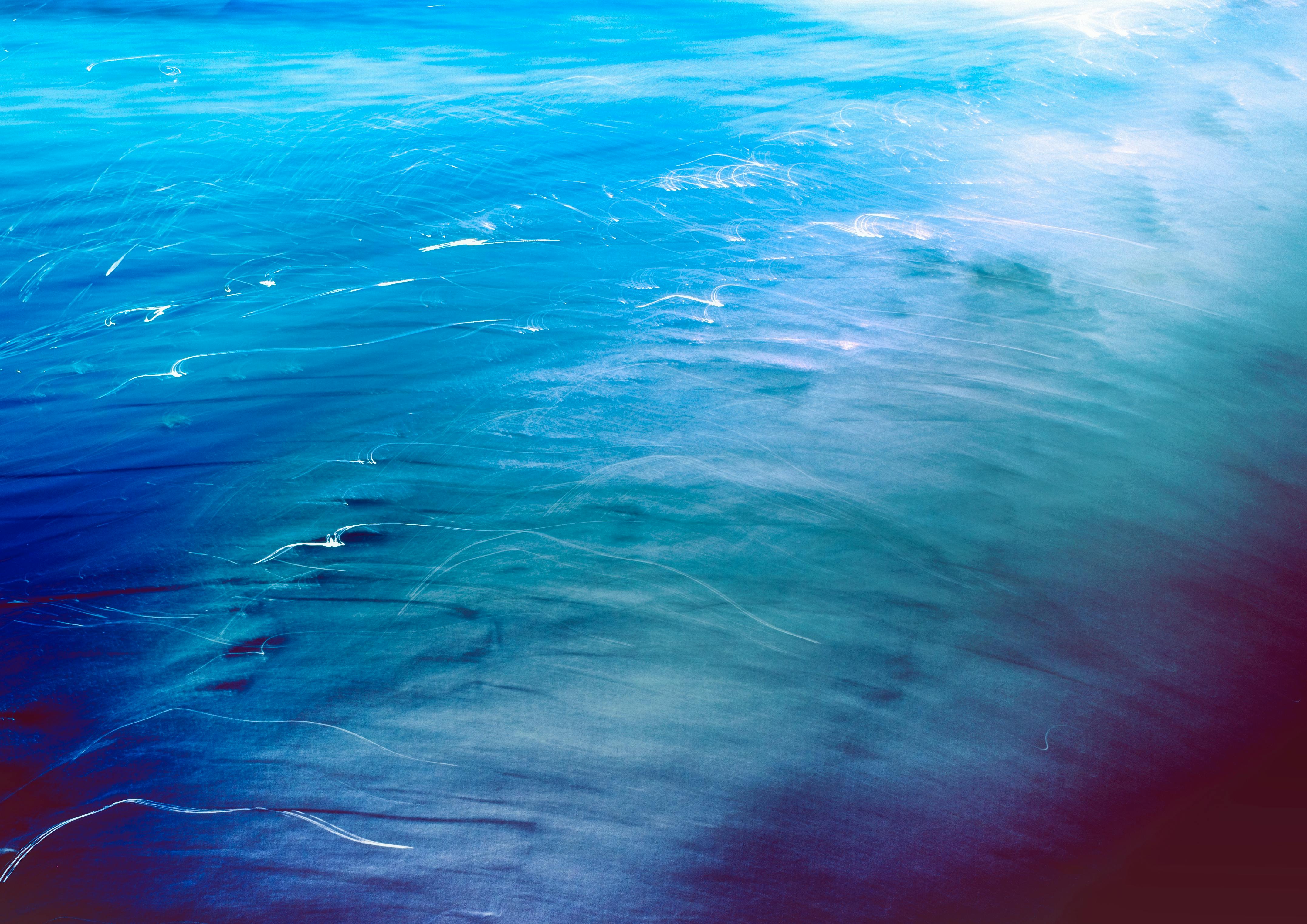 Abstract artistic photo capturing the blurred motion of ocean waves with a blue hue.