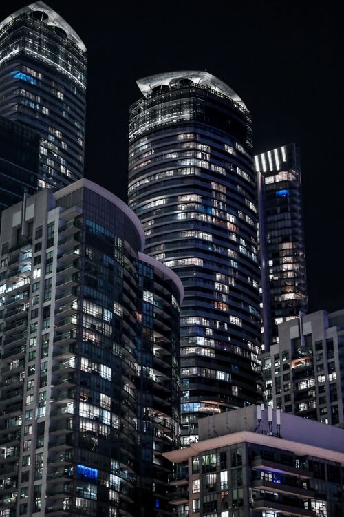 Free Vertical view of contemporary skyscrapers in a vibrant city at night, showcasing urban architecture. Stock Photo