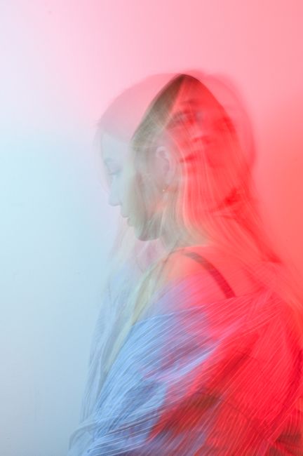 Surreal blurred portrait of a woman in vibrant red and blue tones.