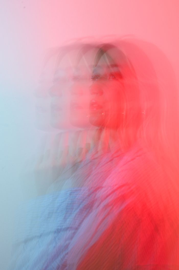 Blurred multiple-exposure portrait in red and blue light. Photo by Vera Emilie on Pexels.