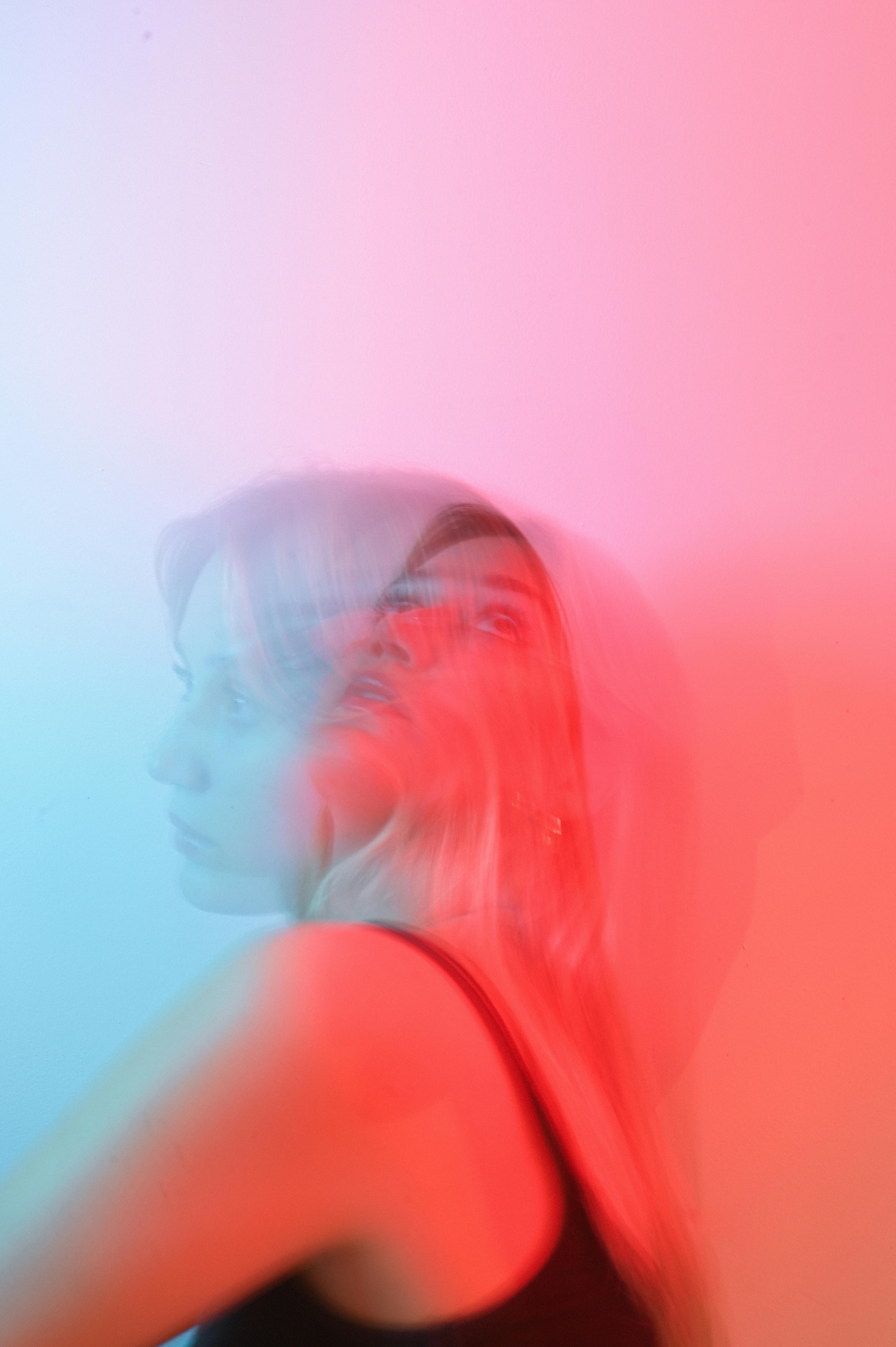 A surreal portrait of a woman with a blurred effect in pink and blue lighting.