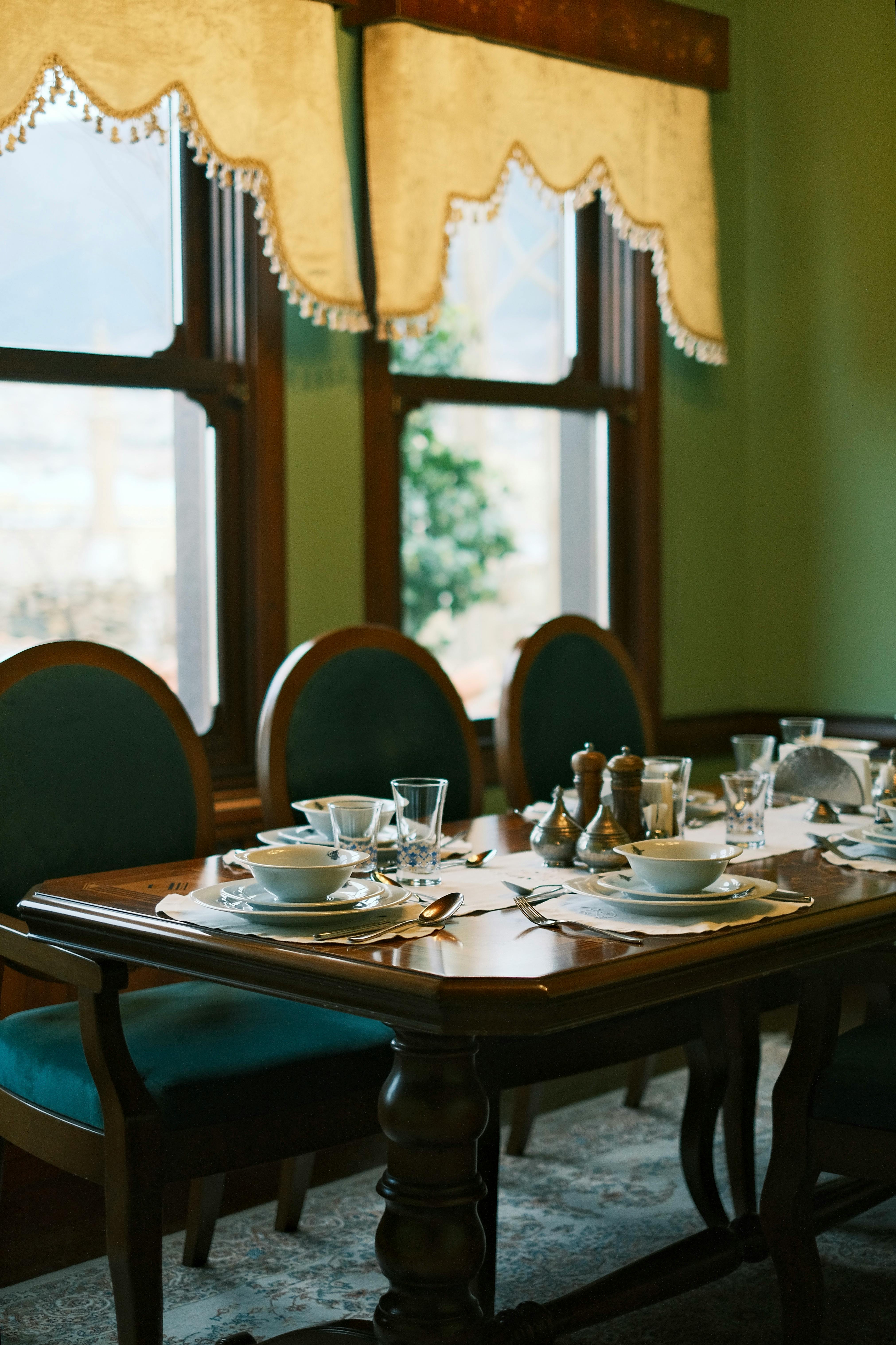 A beautifully set dining table in an elegant room with classic interior decor and natural light.