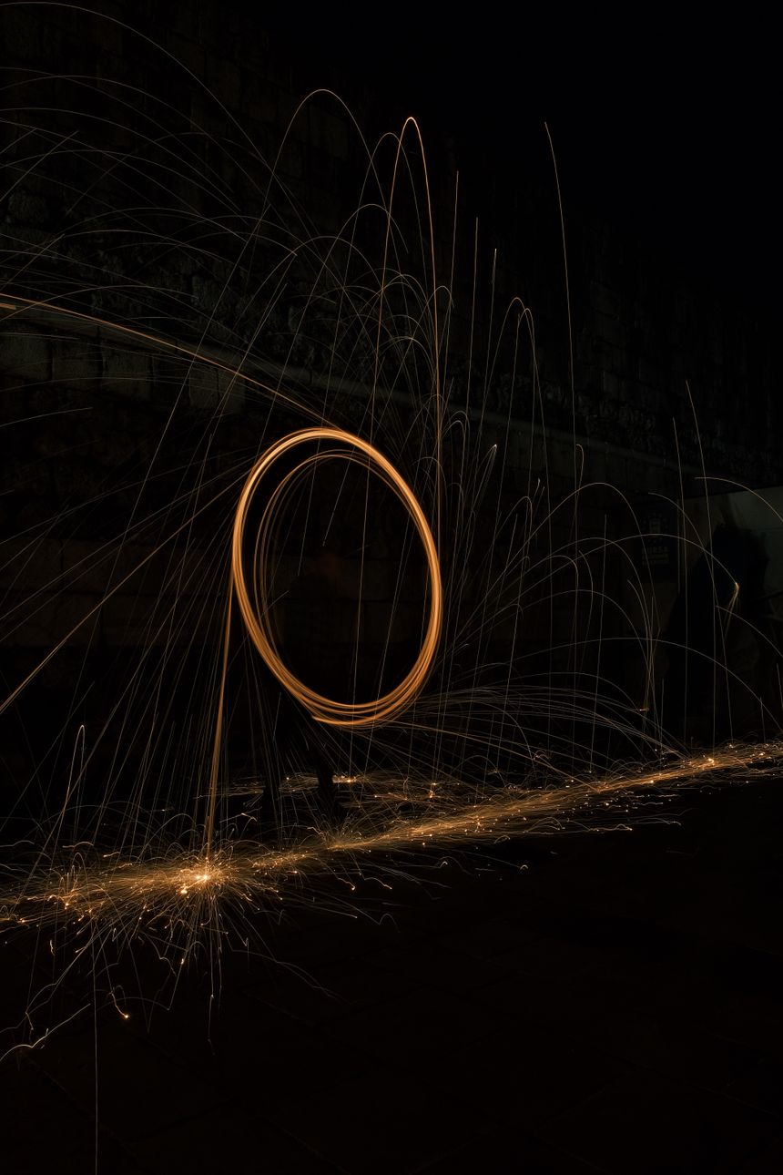 Swirling steel-wool light trails against a night sky — photo by Emre Gencer on Pexels